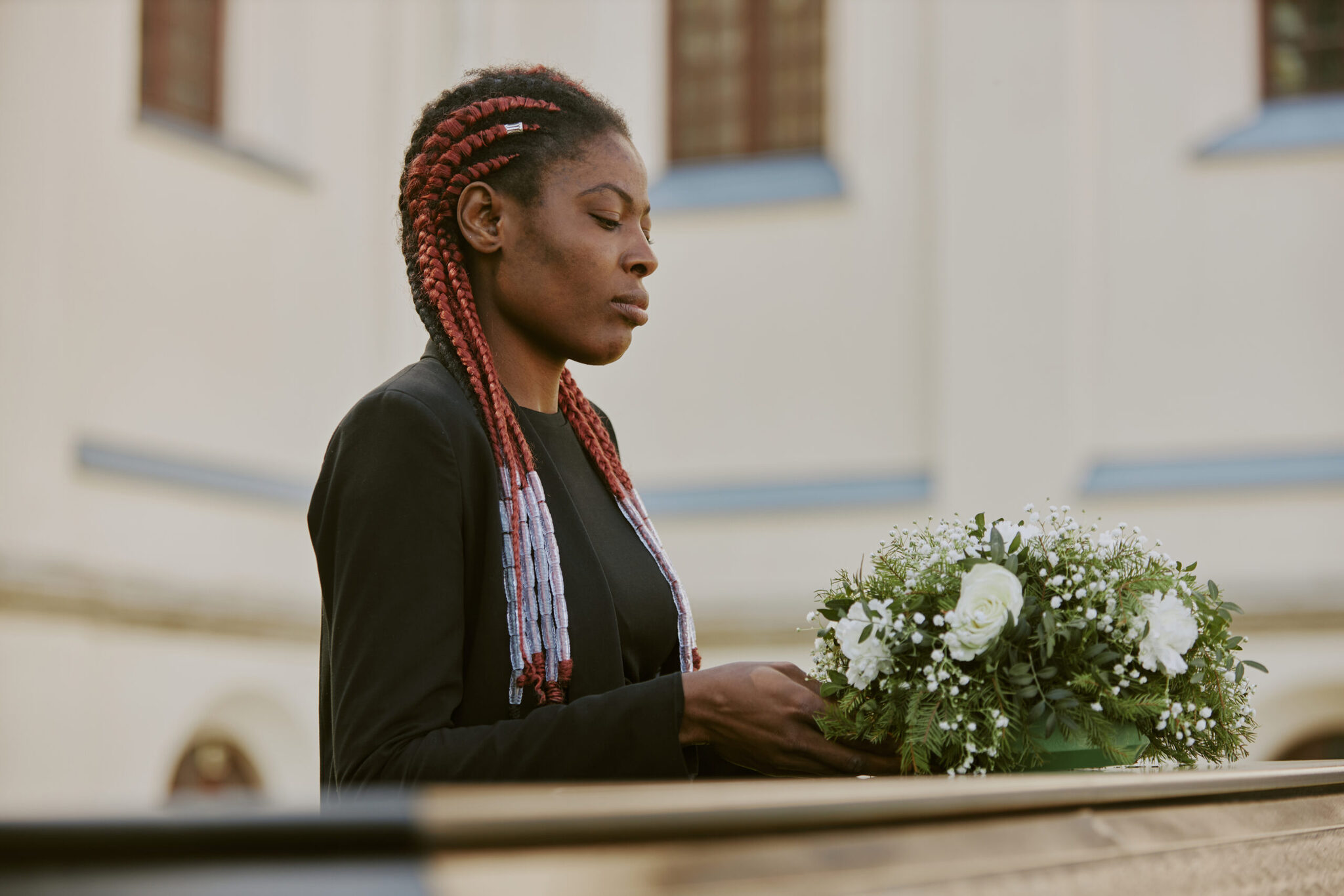 African american woman putting bouquet on coffin