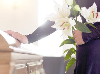 Woman standing with flowers by coffin